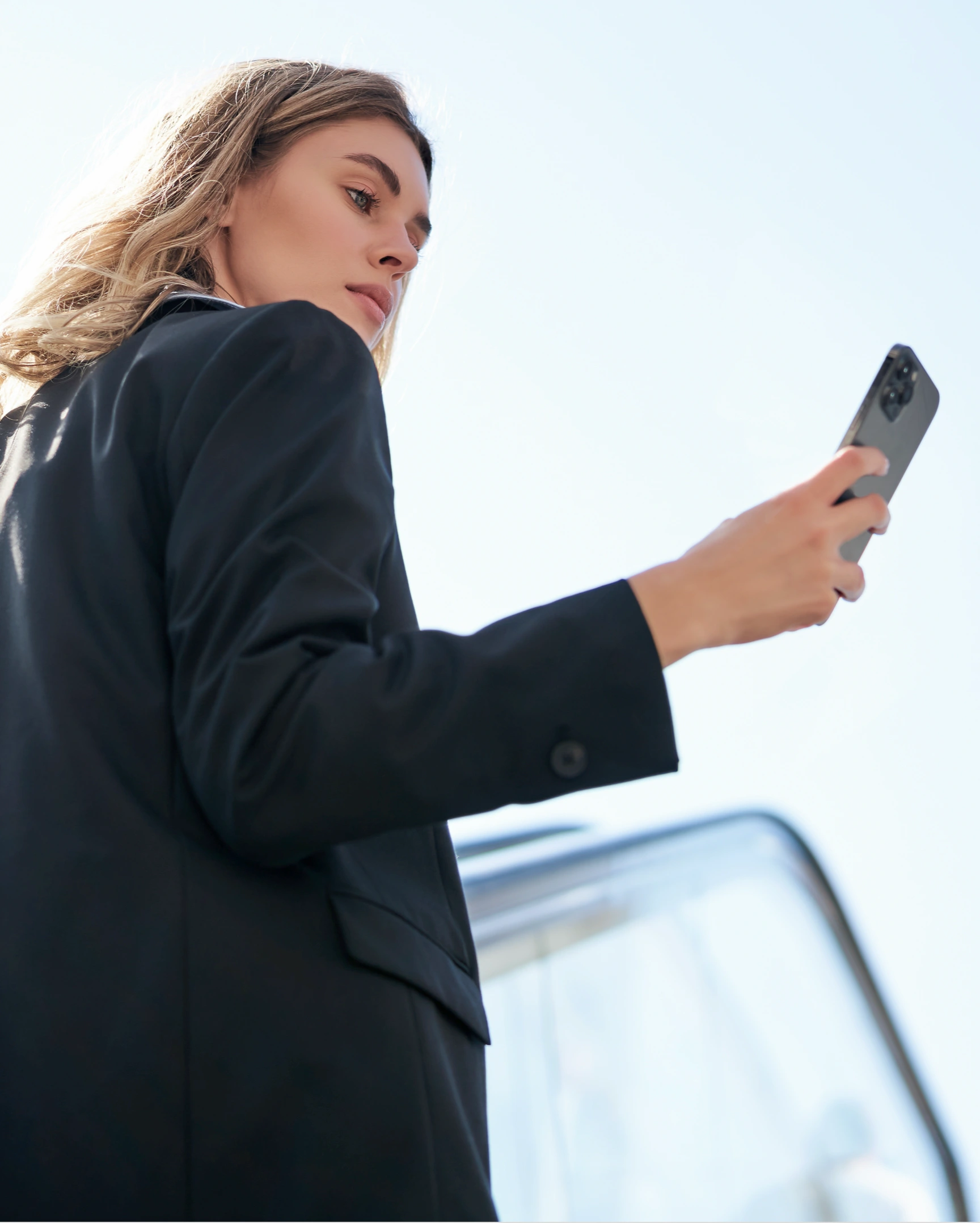 Woman holding smartphone in sunlight.